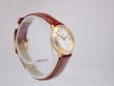 Angled side view of the watch on a clear stand, highlighting the dial and the brown leather strap.