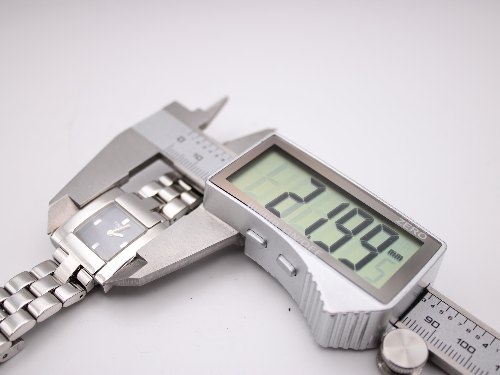 Digital caliper measuring the case diameter of the Tissot watch, displaying a precise measurement of 21.99mm.