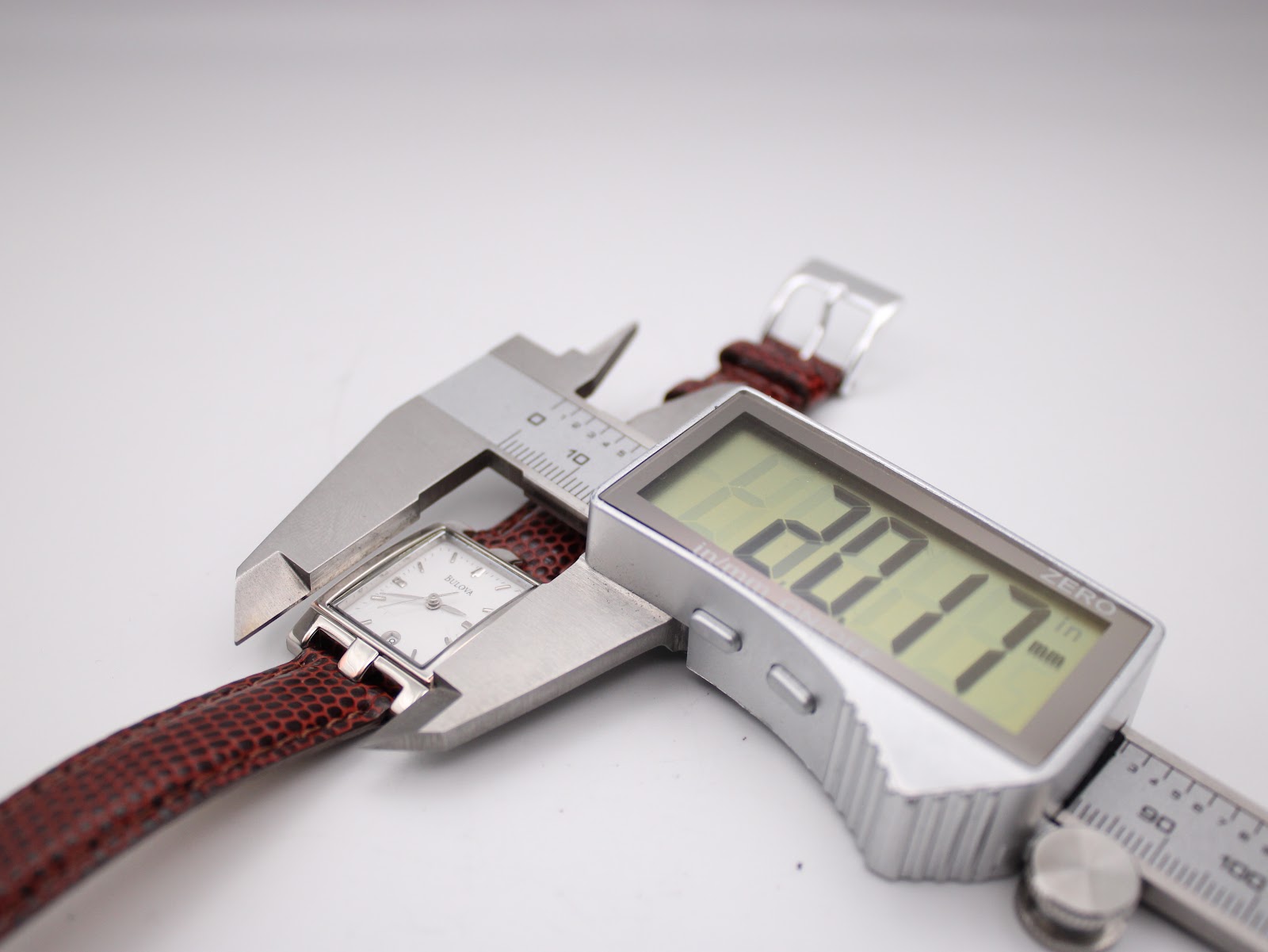 Digital caliper measuring the Bulova watch case, displaying a precise width of 20.17mm.