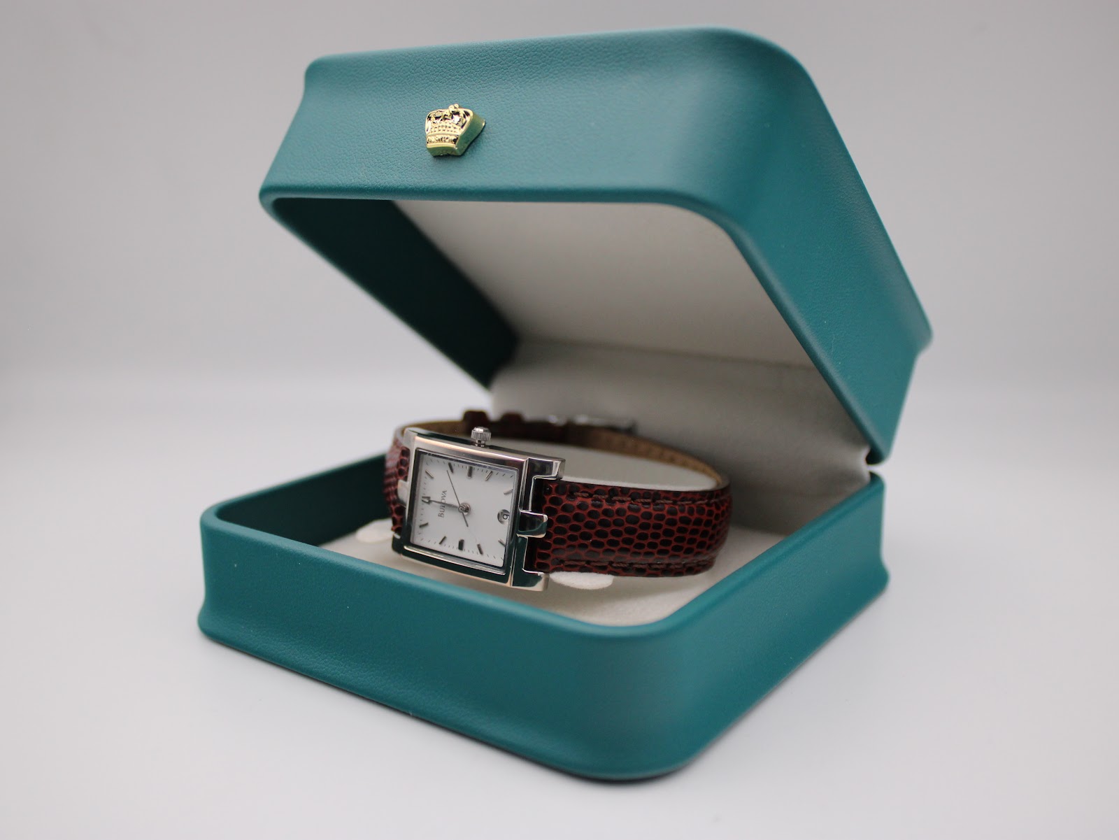 The Bulova watch displayed open in a dark green presentation gift box with a small gold crown accent.