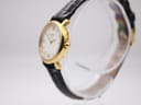 Angled side view of the Tissot C226K watch, showing the gold plated case and crown on a clear stand.