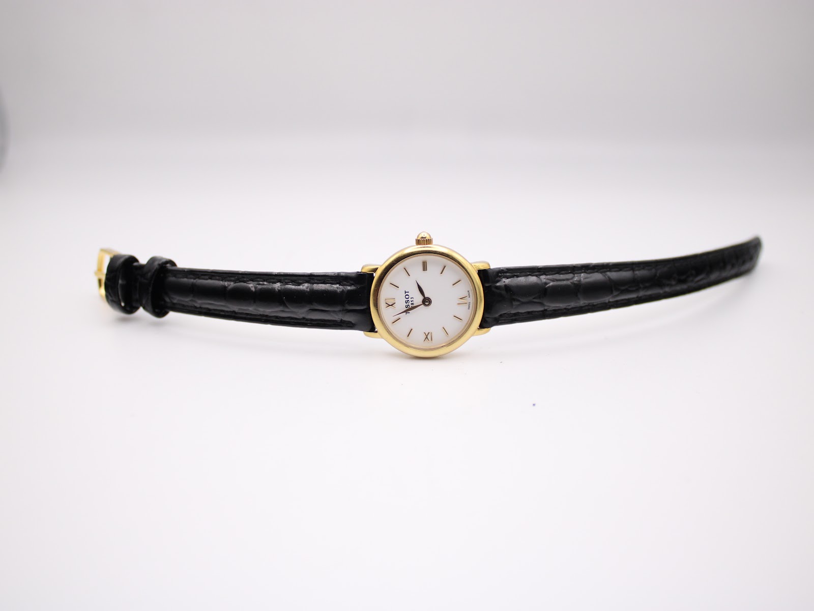 Top-down view of the Tissot C226K watch laid flat, displaying the gold case and the full length of the black croc-effect leather strap.