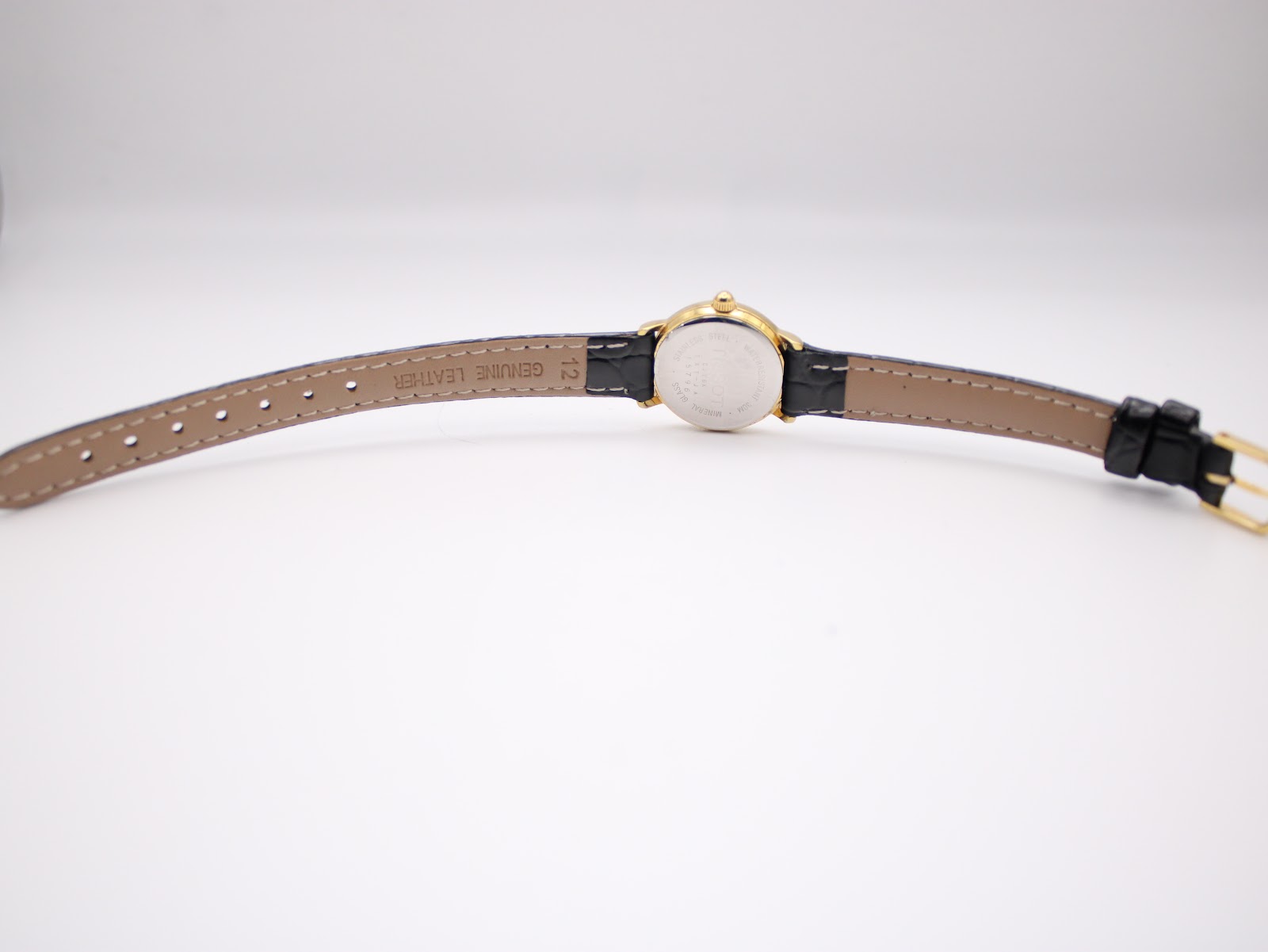 Back view of the Tissot C226K watch and strap, showing the underside of the black leather strap with "GENUINE LEATHER" and "12" embossed, and the gold buckle.