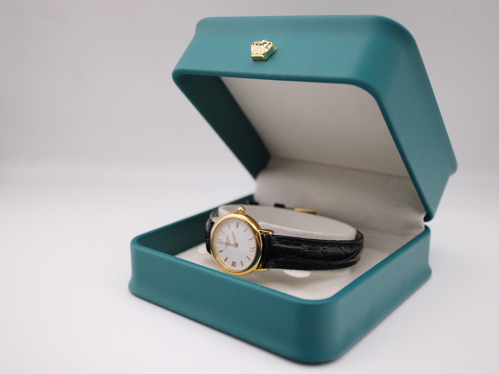 The Tissot C226K watch displayed open in a teal-coloured presentation box with a gold crown emblem on the lid.