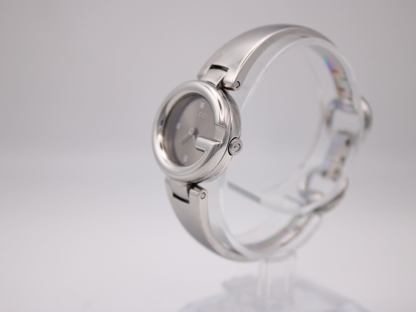 Angled side view of the Gucci 134.5 watch showcasing the integrated stainless steel bangle bracelet on a display stand.