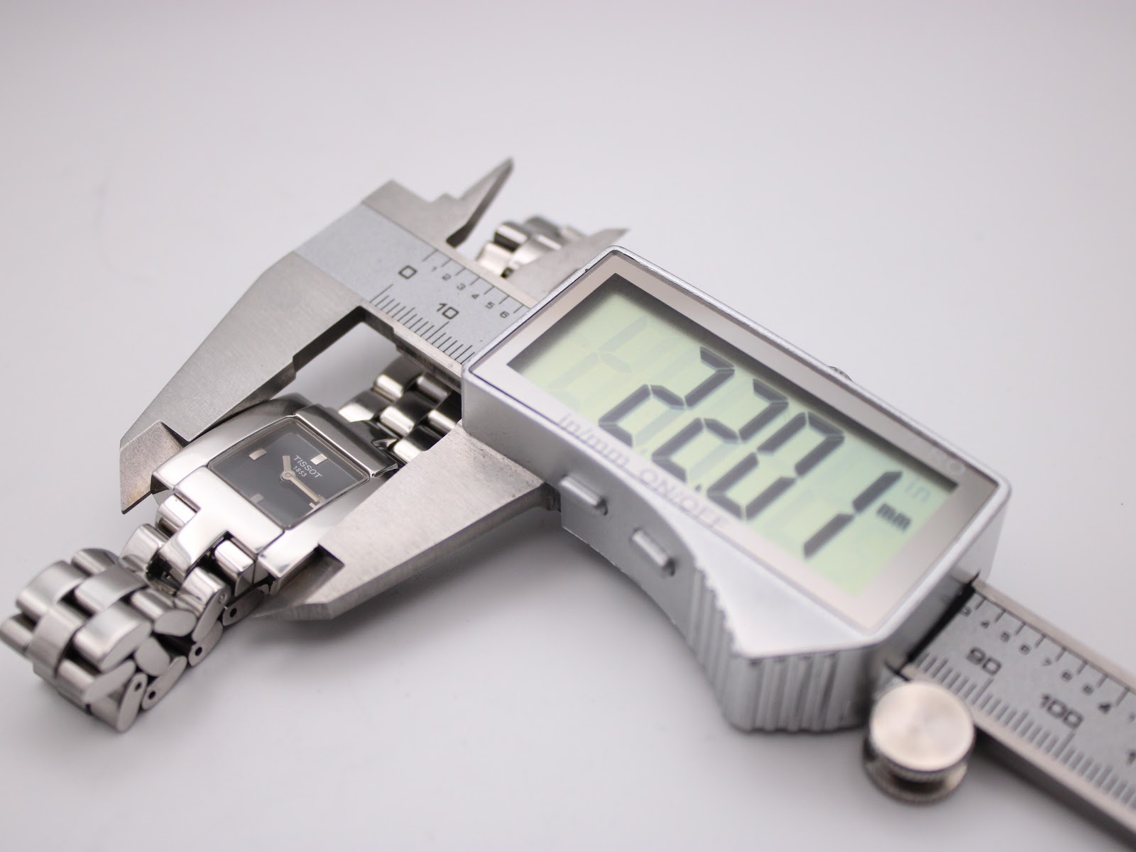 Digital caliper measuring the width of the Tissot L730K watch case, showing a precise measurement of 22.07mm.