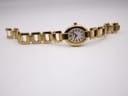 Top-down view of the gold-tone Tissot G332 watch laid flat, showcasing the full length of its integrated steel bracelet.