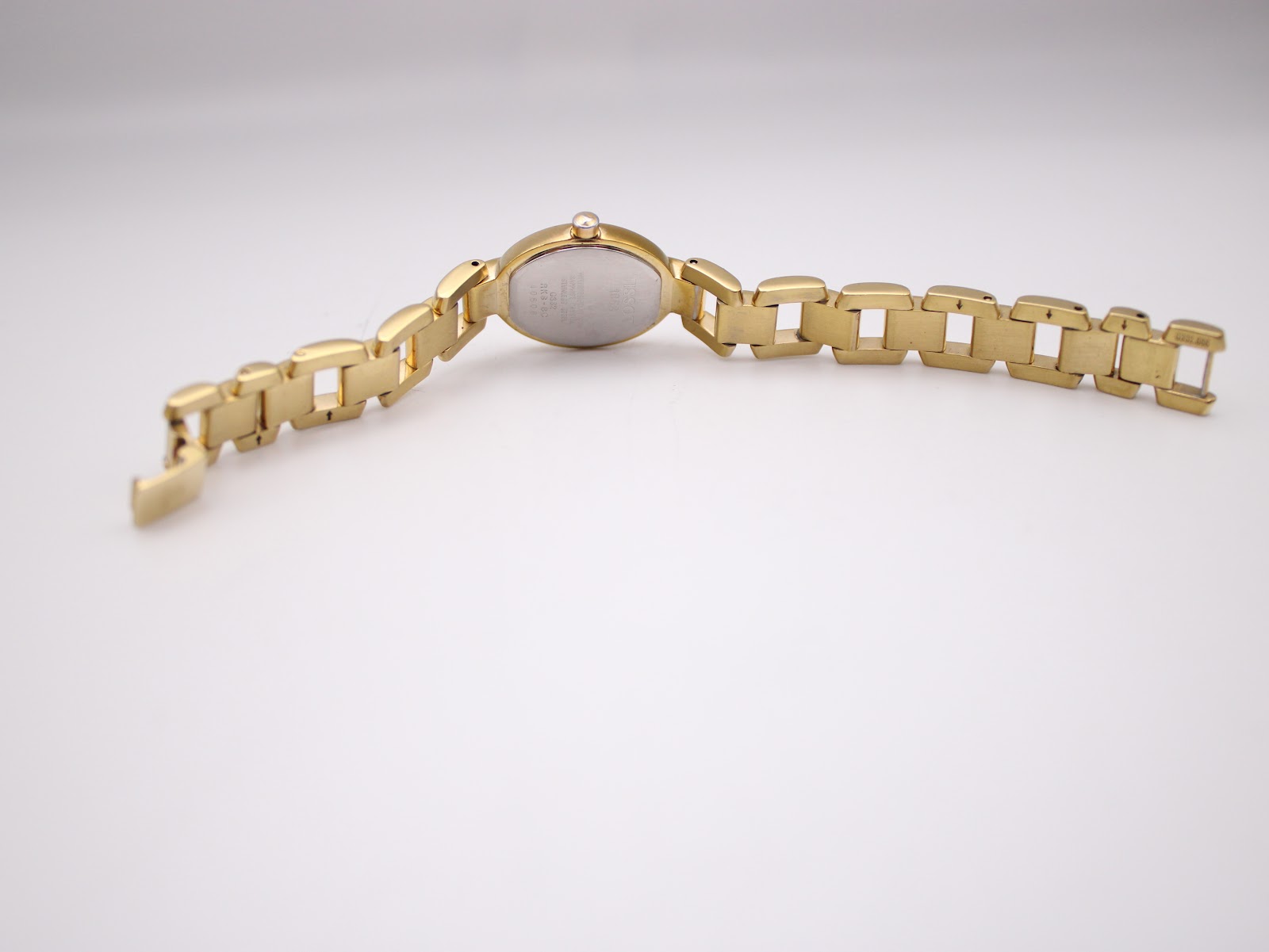 Rear view of the Tissot G332 watch laid flat, displaying the case back and the full extent of the gold-tone bracelet.