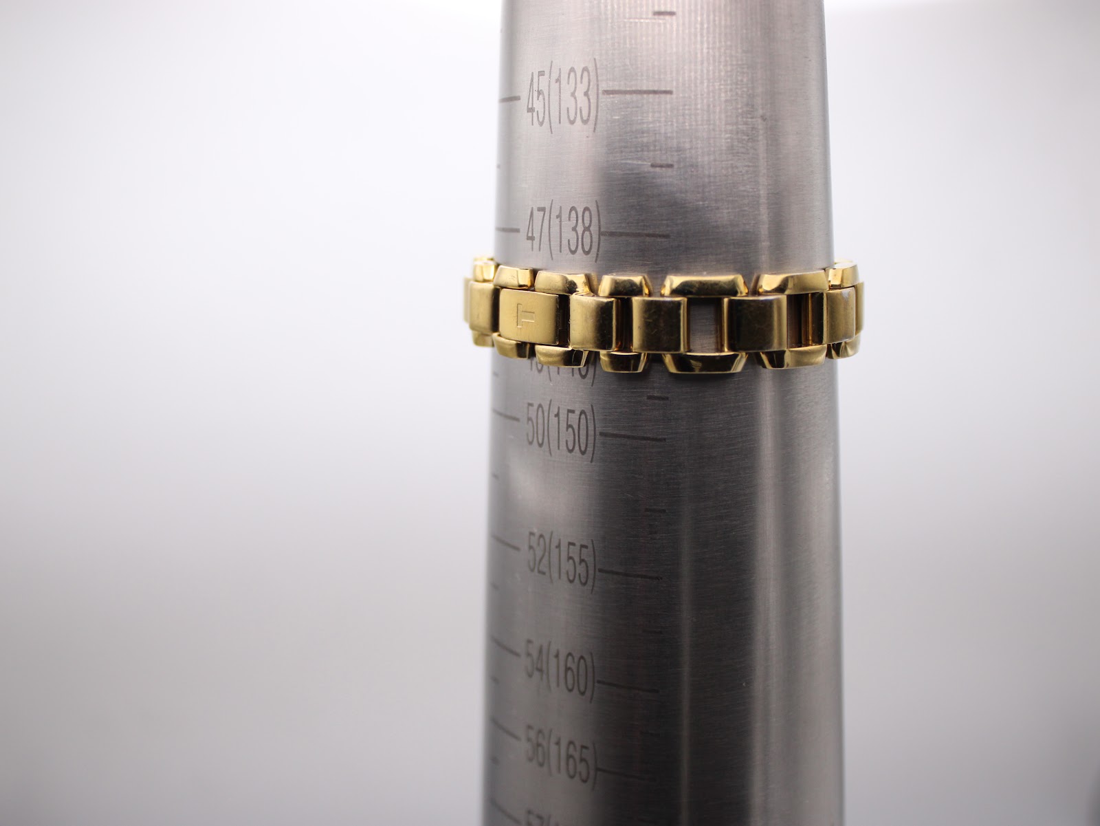 Close-up of the gold-tone Tissot bracelet wrapped around a watch sizing cone, indicating a wrist circumference measurement of approximately 138mm.