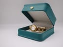The gold-tone Tissot G332 watch resting inside an open teal presentation box with a cream interior.