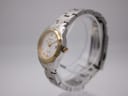 Angled side view of the Tissot watch on a clear display stand, showing the curved case and bracelet links.