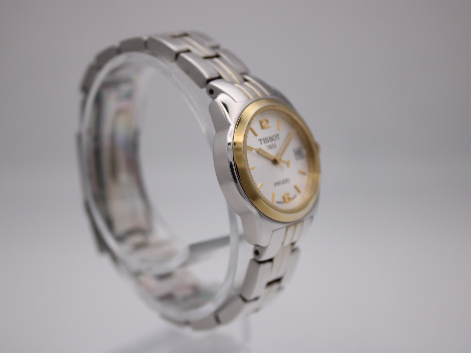 Another angled side view of the Tissot PR 100 watch, highlighting the gold PVD crown and the elegant case profile.