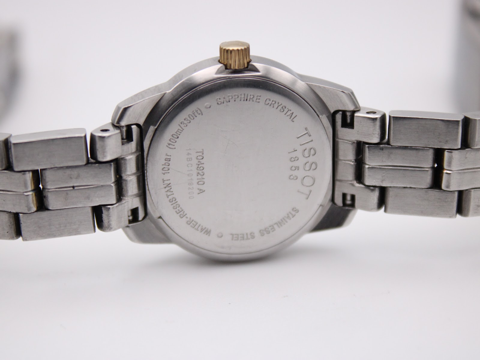 Close-up of the polished stainless steel case back with Tissot 1853, model number T049210 A, and water resistance engravings.