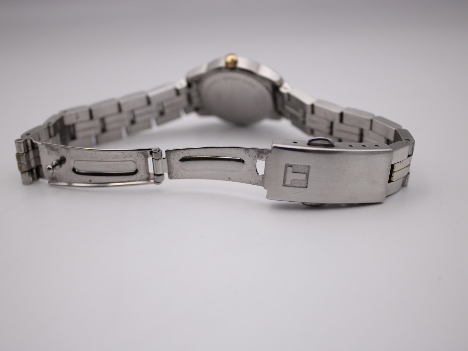 Close-up of the brushed two-tone stainless steel bracelet clasp, featuring the embossed Tissot logo.