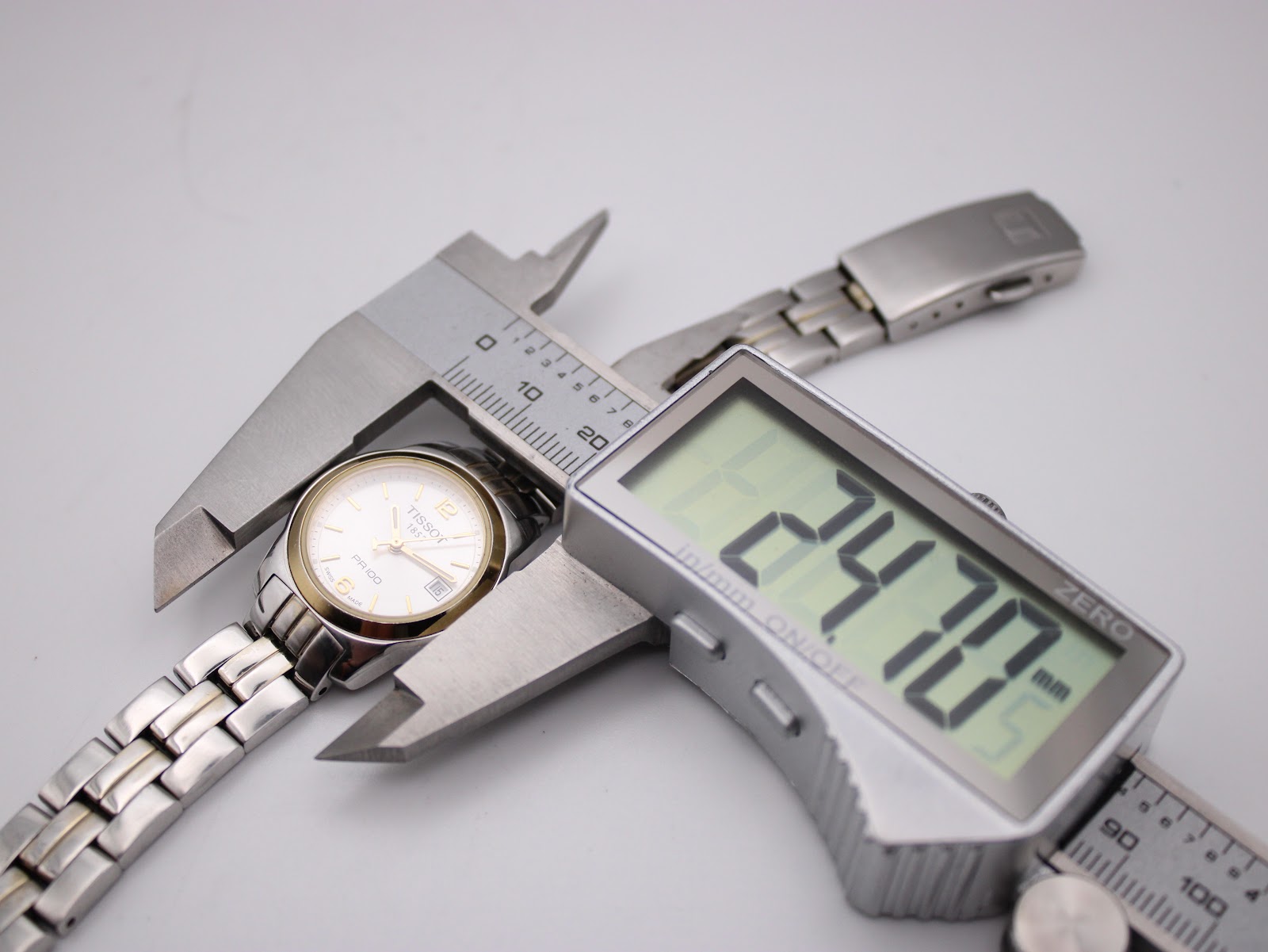 Digital caliper measuring the watch case diameter, showing a precise measurement of 24.70mm.