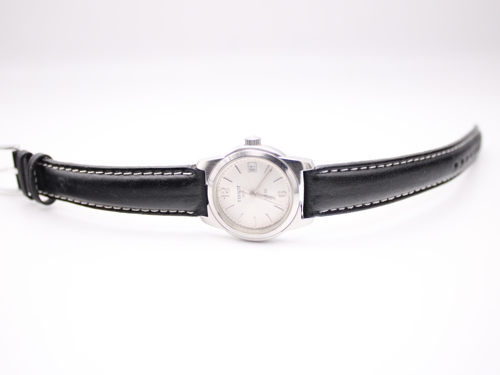 Full front view of the Tissot watch with its black leather strap extended, presented against a white background.
