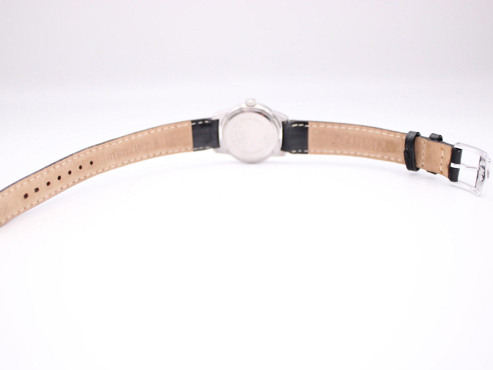 Full back view of the Tissot watch with its black leather strap extended, showing the case back and the strap's lining.