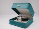The Tissot J326426 watch resting inside a teal display watch box with a gold crown emblem.