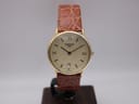 Front view of vintage Tissot T890K gold plated dress watch with champagne Clous de Paris dial and brown croc-effect leather strap, displayed on a watch stand.