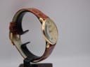Another side view of the Tissot T890K watch on a stand, highlighting the slim case and the texture of the brown leather strap.