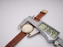Overhead view of the Tissot T890K watch with a digital caliper measuring the case diameter as 33.64mm.