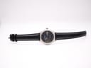 Full length view of the Tissot watch with black leather strap laid flat on a white background.