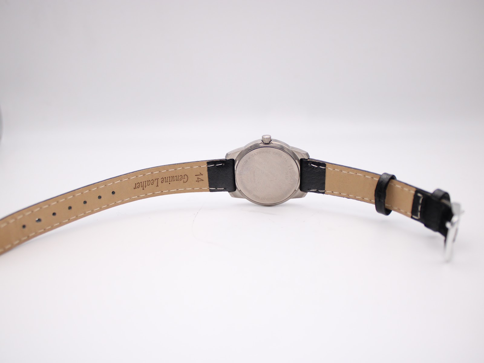 Underside view of the Tissot watch showing the case back and 'genuine leather' strap with 14mm lug width visible.