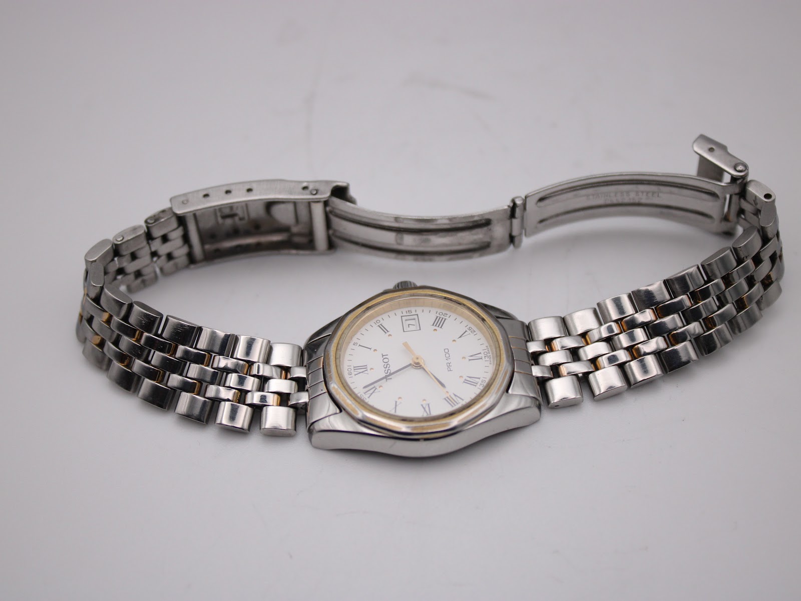 Overhead view of the Tissot watch laid flat with its two-tone bracelet unclasped, showing the full length of the bracelet and the signed deployant clasp.