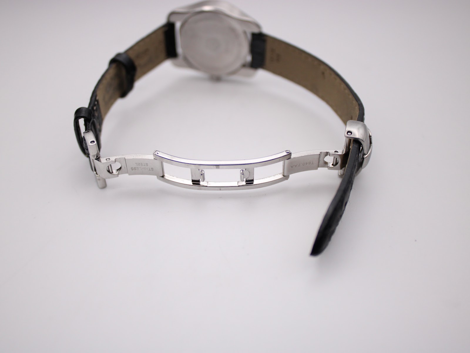 Close-up of the polished stainless steel butterfly deployment clasp from the Tissot watch, showing 'STAINLESS STEEL' engraving.