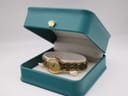 The gold tone Tissot watch displayed inside a decorative teal jewellery box with a gold crown emblem.