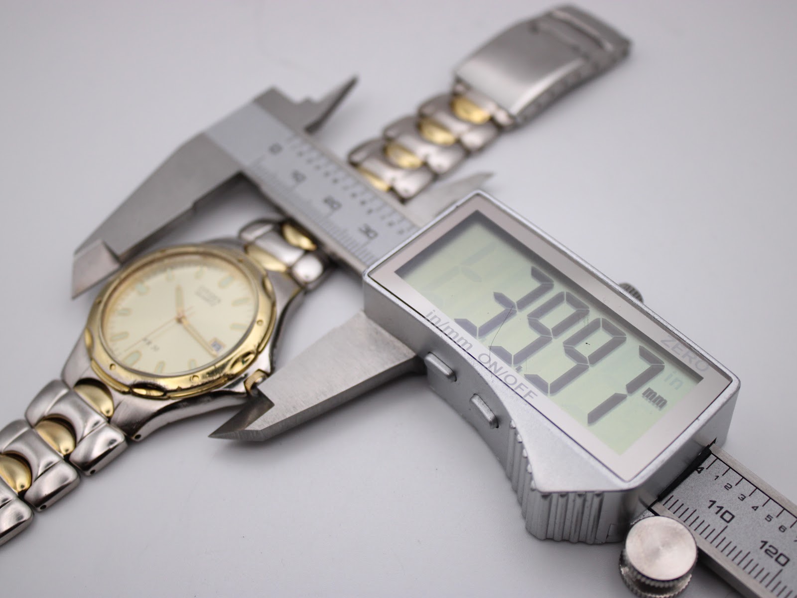 Digital caliper measuring the watch case diameter at 39.97mm, with the two-tone bracelet visible.