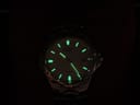 Dark shot of the Citizen watch dial, demonstrating the luminous gold-tone hands and hour markers glowing.