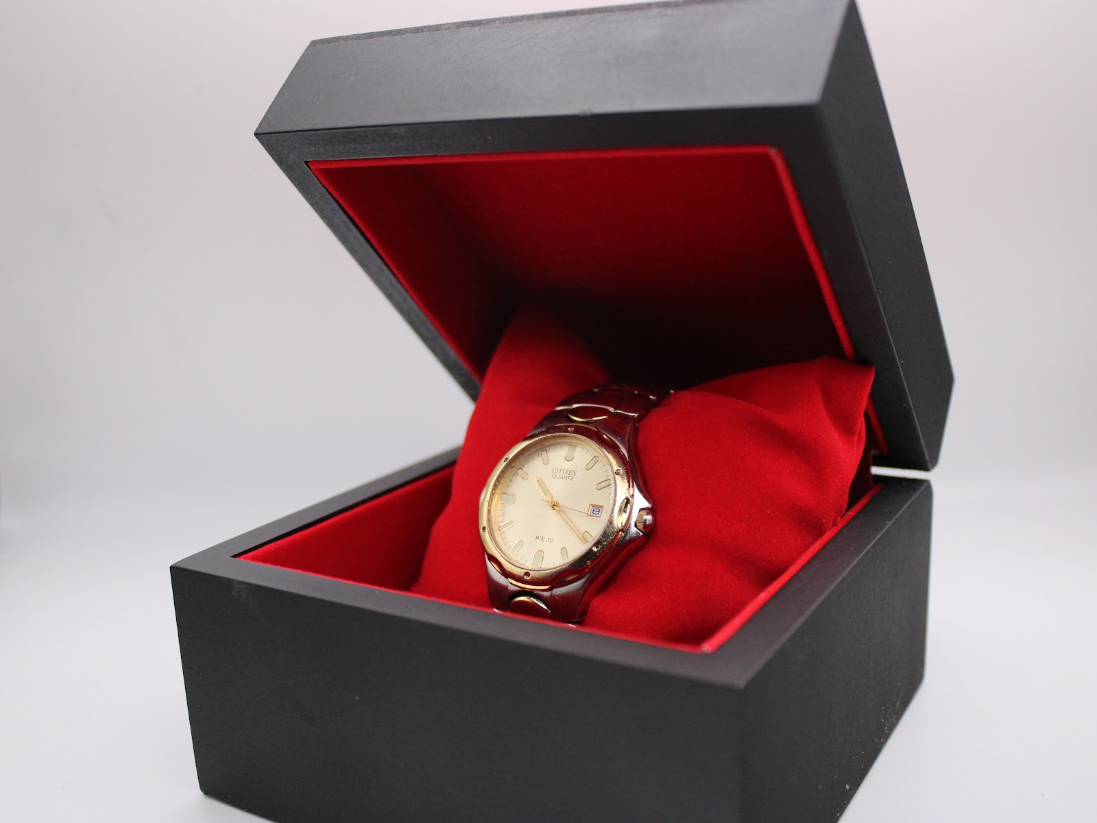 The Citizen watch presented inside an open black box with a red cushion interior.