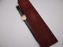 Overhead view of the watch and its original red velvet Raymond Weil protective pouch, showing the gold branding on the pouch.