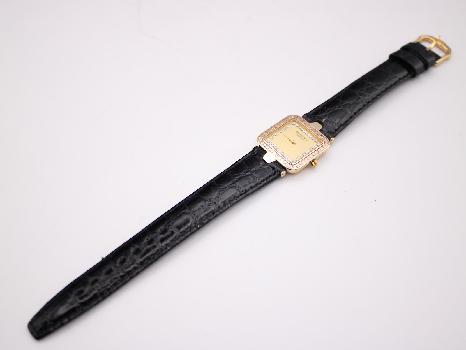 Full length view of the Raymond Weil watch with its black leather strap laid flat, showcasing the strap's length.