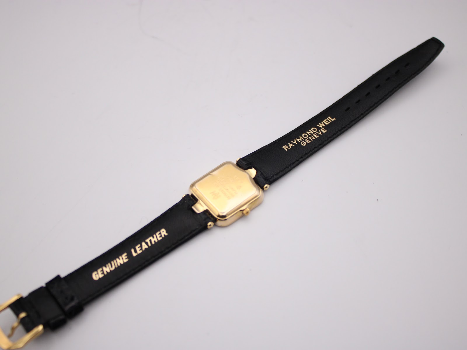 Rear full length view of the Raymond Weil watch and strap, showing the case back details and the gold branding on the strap interior.