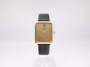 Front view of the gold plated Raymond Weil 713 watch with champagne dial and black leather strap, on a white background.