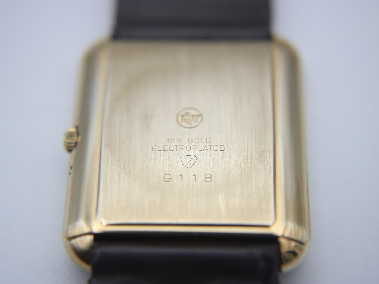 Close-up of the polished gold electroplated case back, engraved with "RW" logo, "18K GOLD ELECTROPLATED", "10M", and model number "9118".
