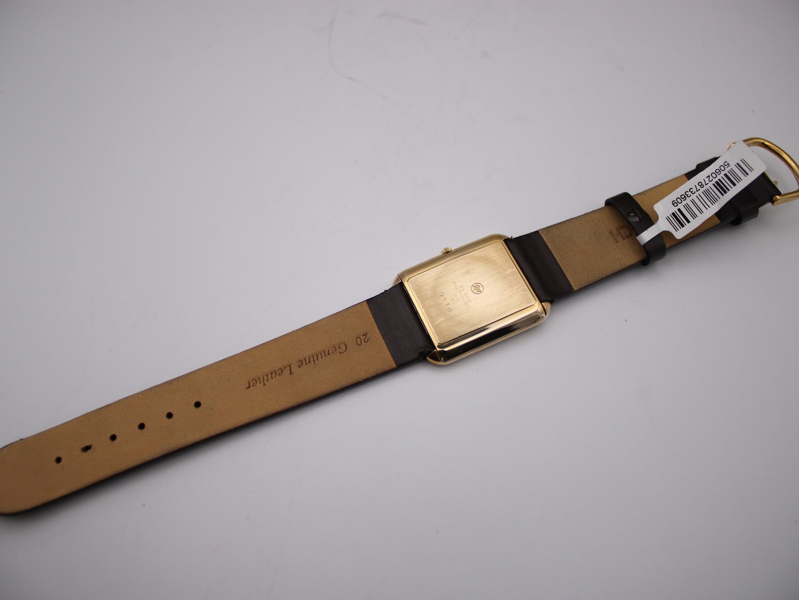 Underside view of the Raymond Weil 9118 showing the genuine leather strap with "20 Genuine Leather" printed, and the gold electroplated case back.