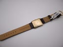 Underside view of the Raymond Weil 9118 showing the genuine leather strap with "20 Genuine Leather" printed, and the gold electroplated case back.