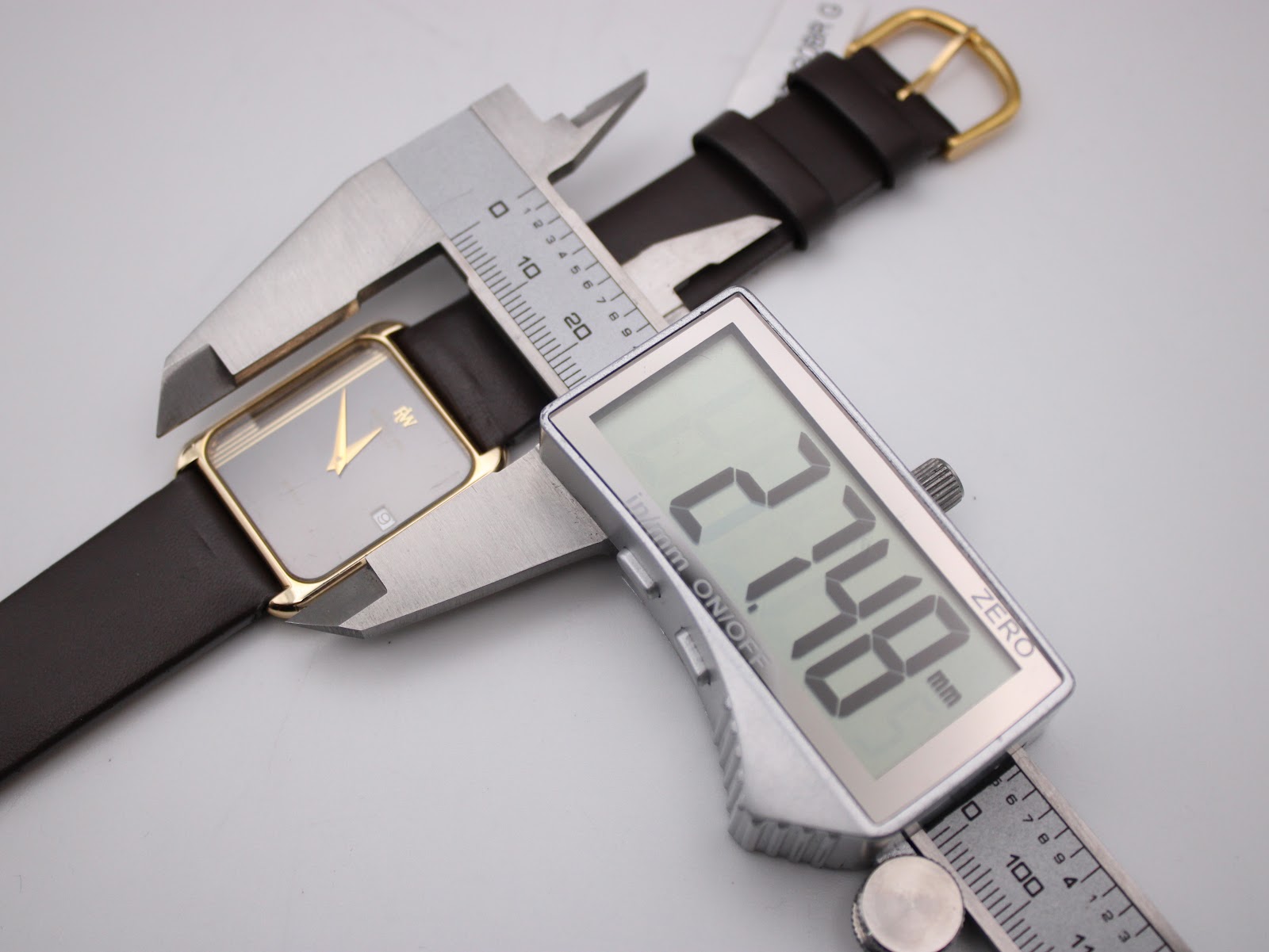 Digital caliper measuring the case width of the Raymond Weil 9118, displaying an exact measurement of 27.48 mm.