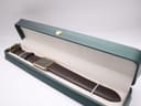 The Raymond Weil 9118 watch and dark brown strap nestled inside an open green aftermarket presentation box.