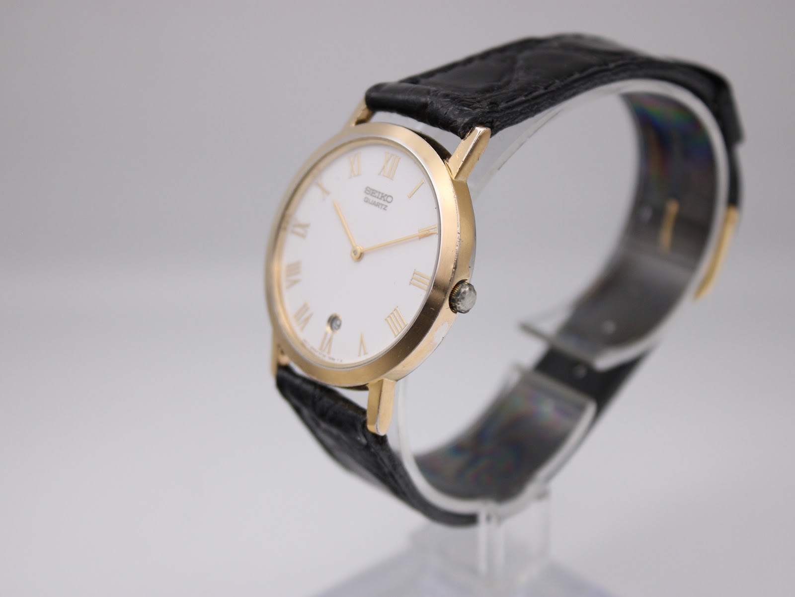 Side profile of vintage Seiko Quartz watch showing slim gold-tone case and crown.