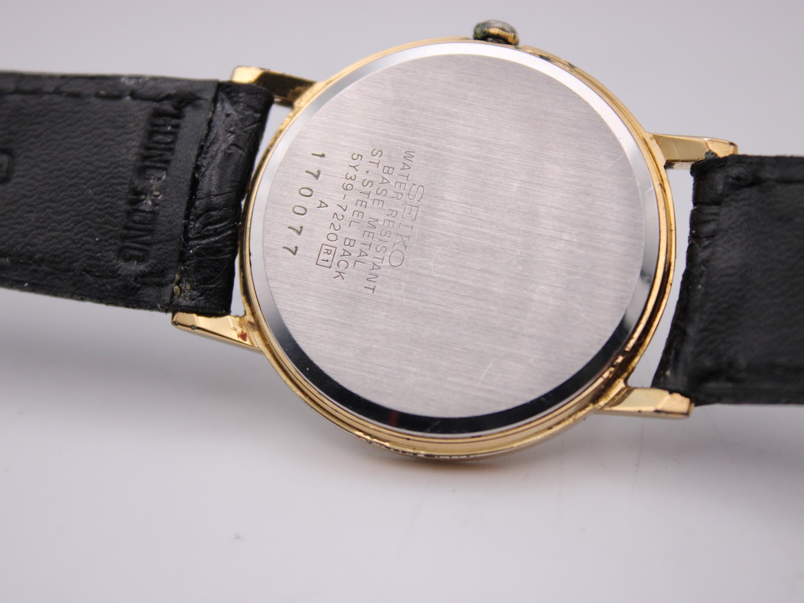 Detailed view of white dial with gold Roman numerals and 6 o'clock date window on Seiko 5Y39-7220.