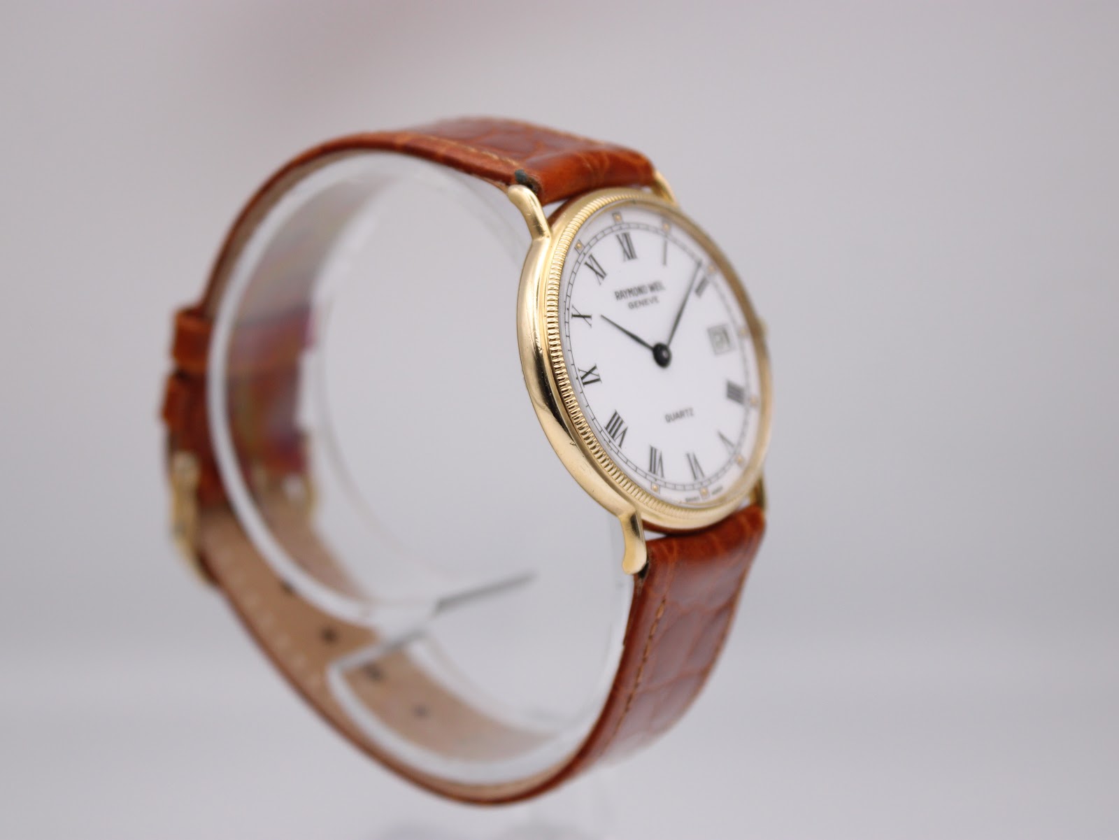 Close-up side view of the Raymond Weil 5514 watch, highlighting the gold case finish and textured bezel.