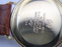 Close-up of the watch case back showing "Raymond Weil Geneve", "18 K Gold Electroplated 10 M", "Water Resistant", and model number "5514" with surface scratches.