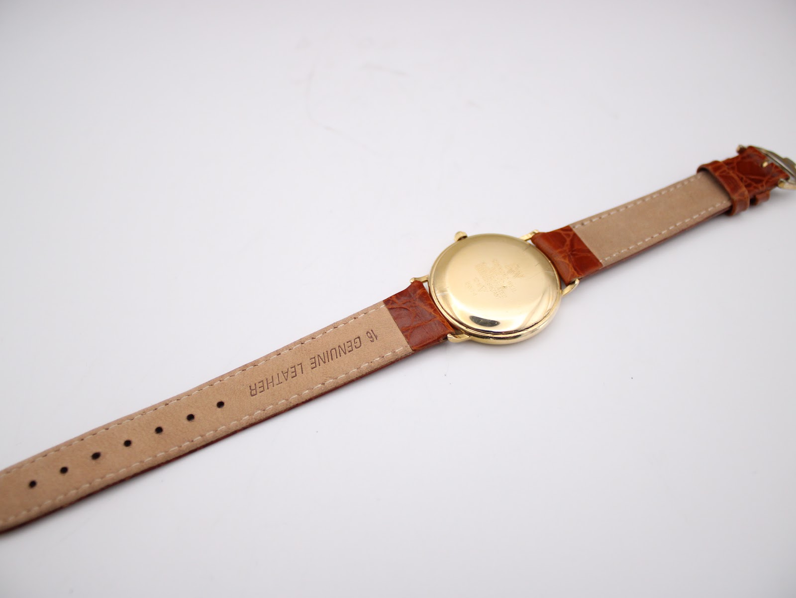 Rear view of the watch and strap, showing the back of the brown leather strap with "16 GENUINE LEATHER" text.