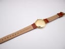 Rear view of the watch and strap, showing the back of the brown leather strap with "16 GENUINE LEATHER" text.