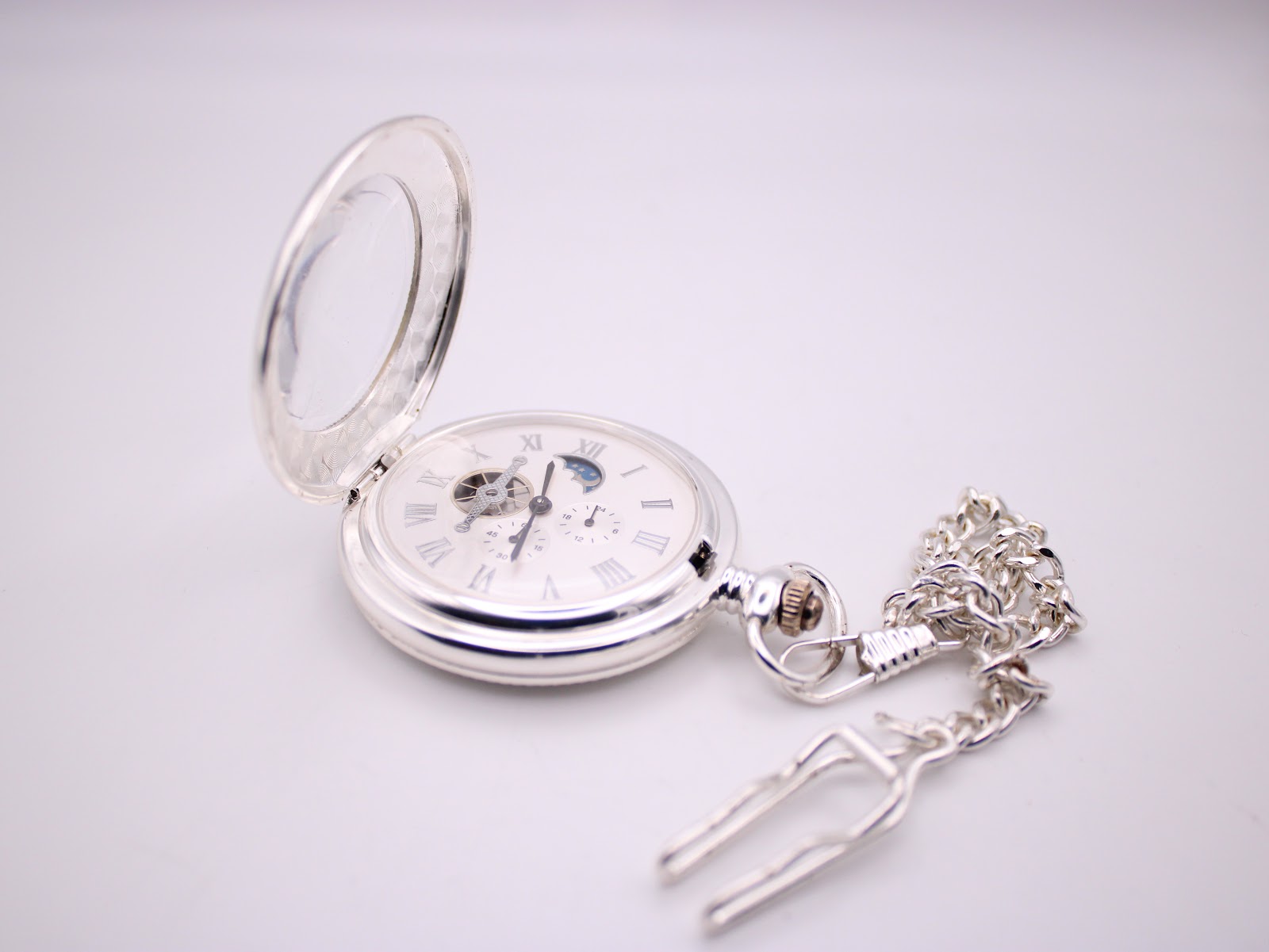 Open view of the silver-plated Heritage Collection pocket watch with its matching chain and T-bar fob, on a white surface.